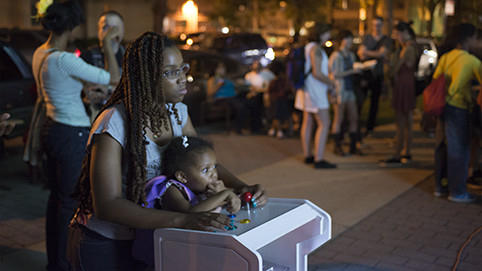 A teen artist helps her young sister try the games. Photo courtesy the Plug-In Studio.