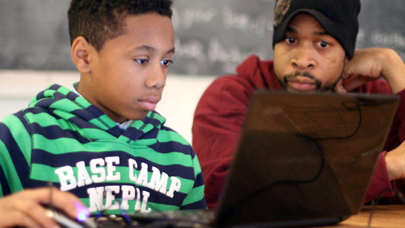 Artist Teacher consults with participant at free video game class.